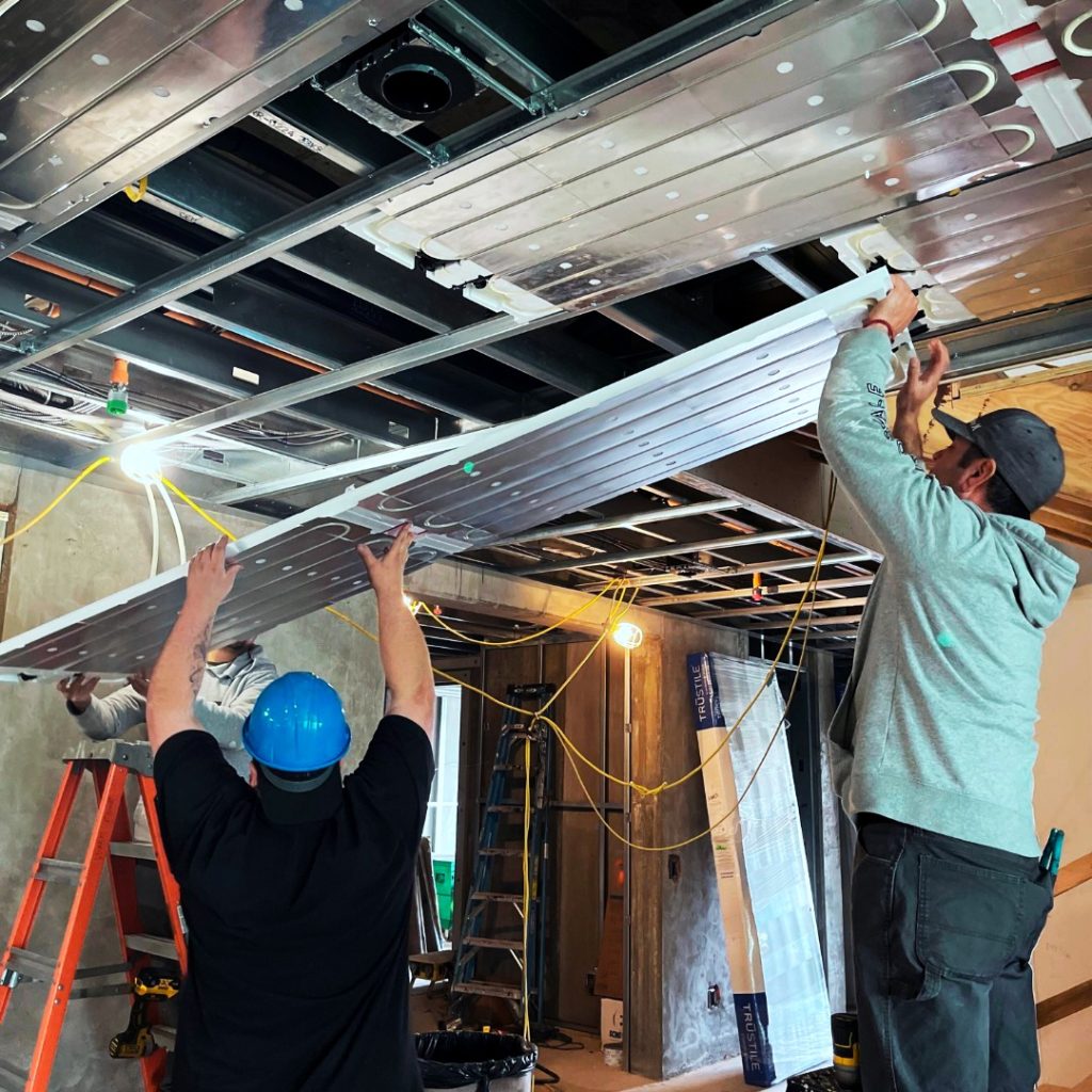 Warm Corp West installing a radiant ceiling in between metal furring channels. The radiant ceiling will provide hydronic radiant cooling and heating.