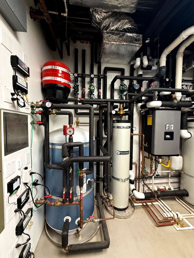 Mechanical room for hydronic system installed to provide heating and cooling via a radiant floor and hydronic fan coil units made by Jaga, managed with Messana Controls.