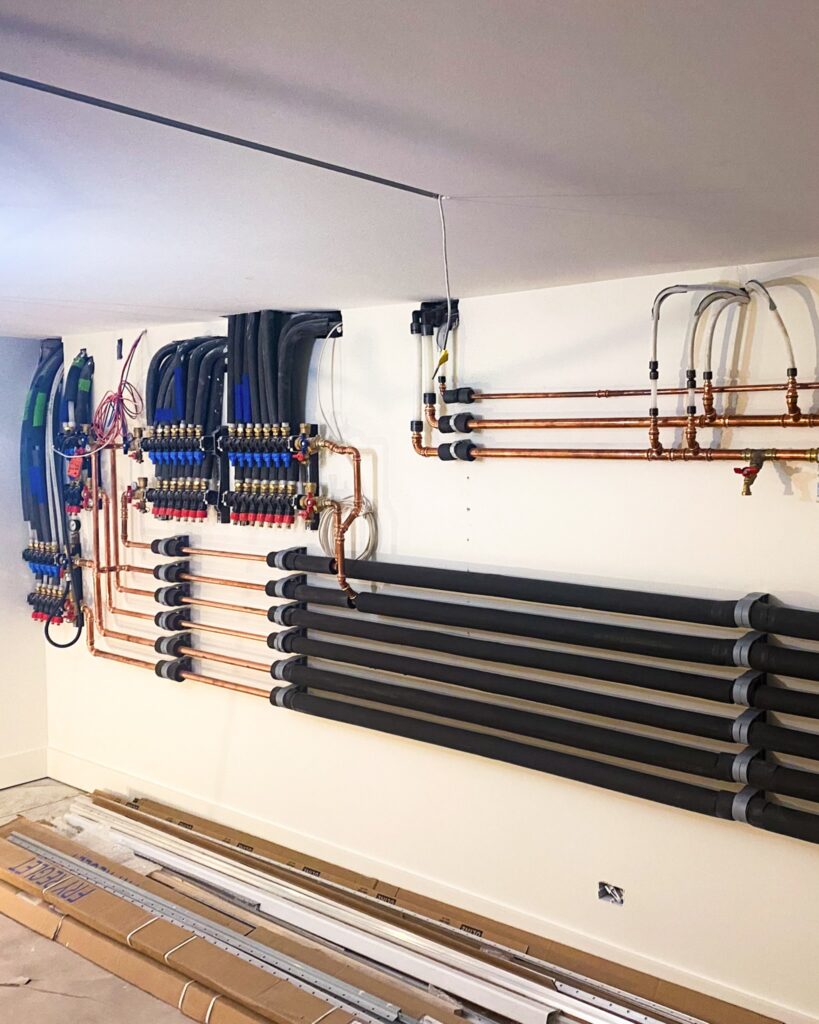 Hydronic manifolds for radiant floor and radiant ceiling heating and cooling powered by geothermal heat pumps and managed via Messana Controls.